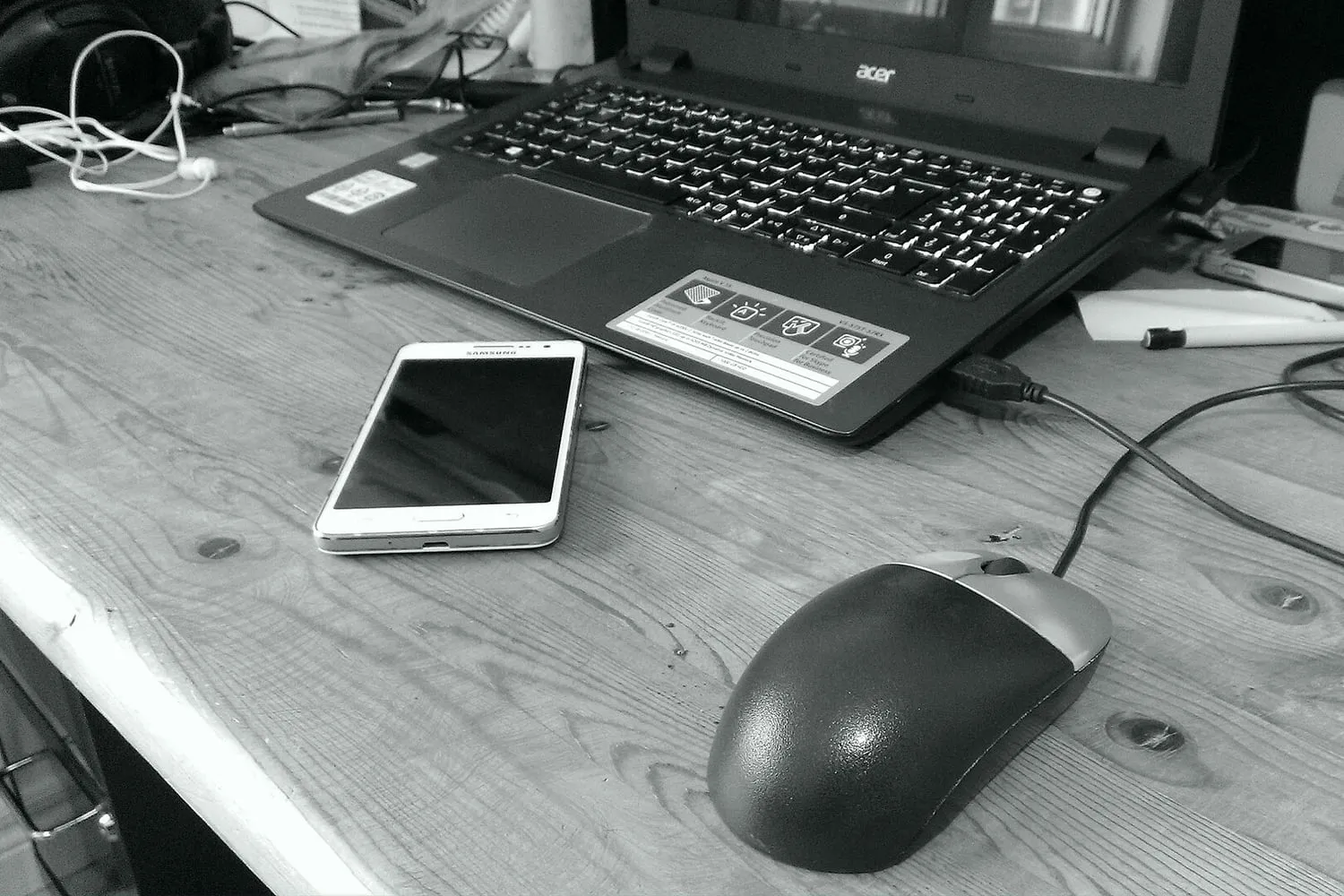 A laptop and a phone on a desk, both switched on